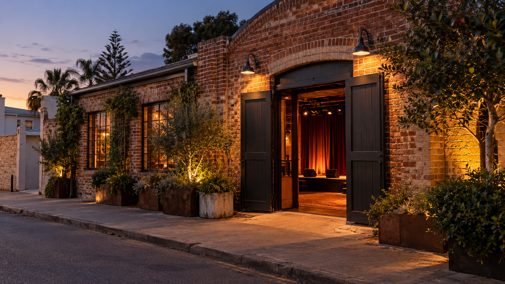 A brick performance venue with a lit doorway at dusk